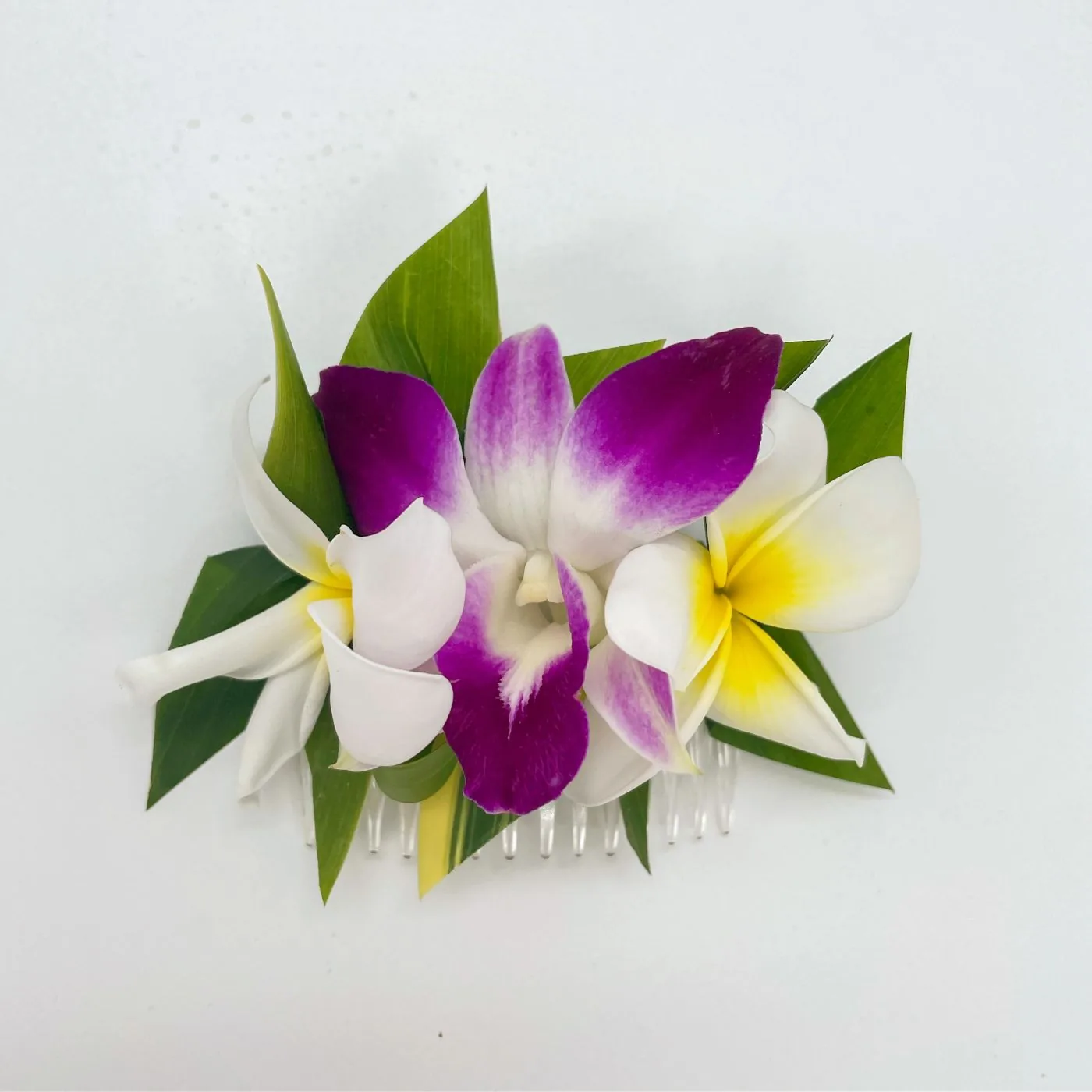 A hair comb of purple dendrobium orchids and white plumeria.